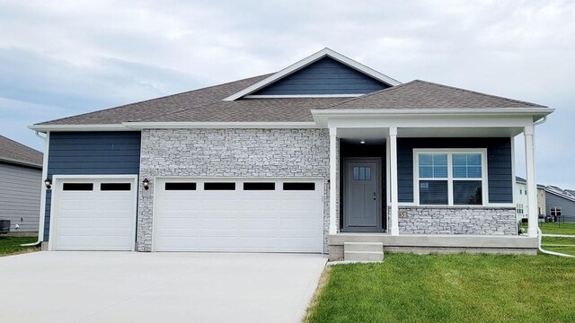 view of front of home featuring a garage, a front yard, and central air condition unit