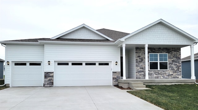 view of front of property featuring an attached garage, covered porch, a shingled roof, and concrete driveway