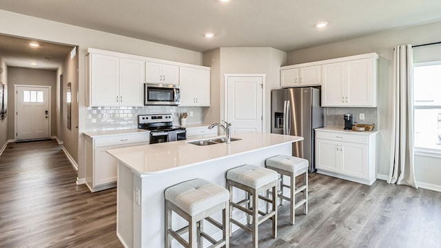 kitchen with appliances with stainless steel finishes, a sink, a breakfast bar area, and wood finished floors