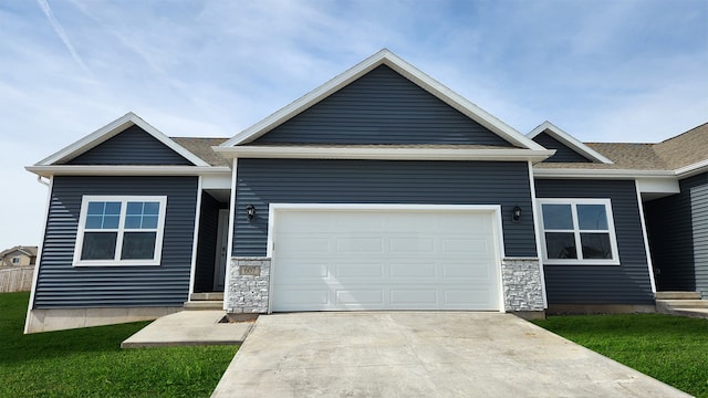 view of front of house with stone siding, concrete driveway, a front lawn, and an attached garage