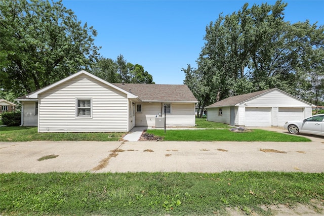 single story home with a garage, an outbuilding, and a front yard