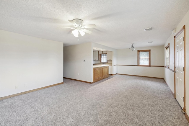 unfurnished living room featuring light colored carpet and a textured ceiling