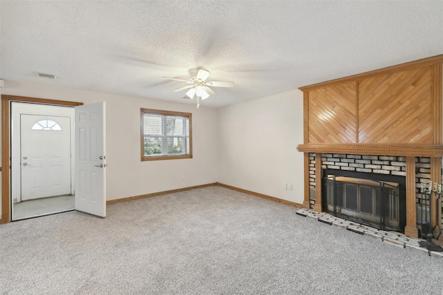 unfurnished living room with wooden walls, a brick fireplace, ceiling fan, a textured ceiling, and carpet floors