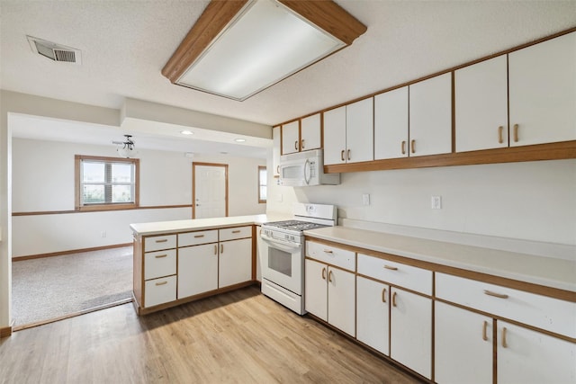 kitchen with kitchen peninsula, white cabinetry, white appliances, and light wood-type flooring