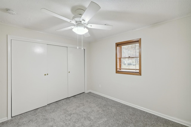 unfurnished bedroom with ceiling fan, a textured ceiling, light carpet, a closet, and ornamental molding