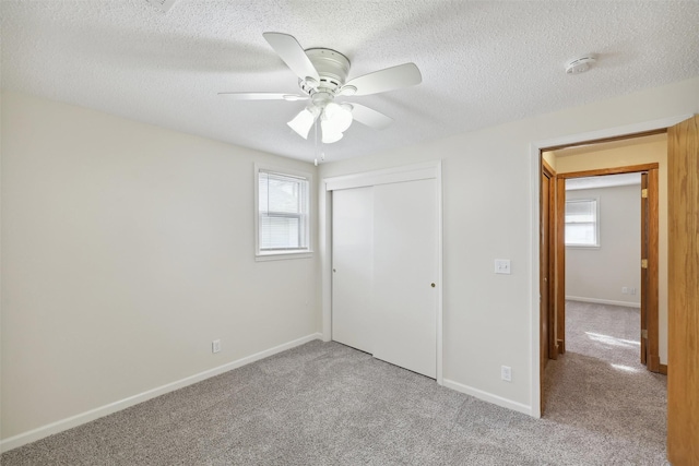 unfurnished bedroom featuring light carpet, a closet, multiple windows, and ceiling fan