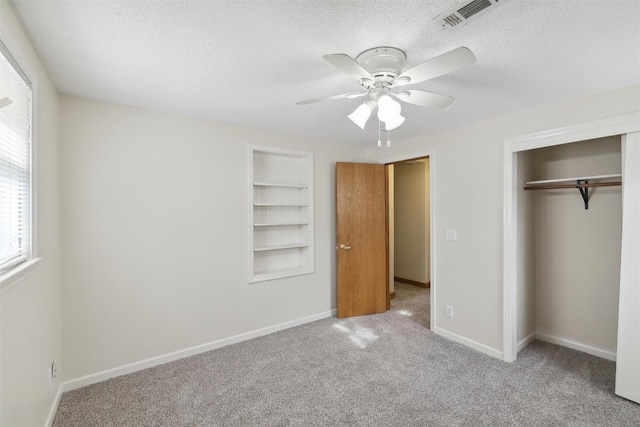 unfurnished bedroom featuring ceiling fan, a closet, light colored carpet, and a textured ceiling