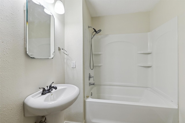 bathroom featuring sink, a textured ceiling, and bathtub / shower combination