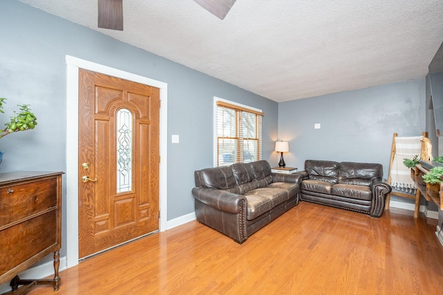 living room featuring ceiling fan, wood-type flooring, and a textured ceiling