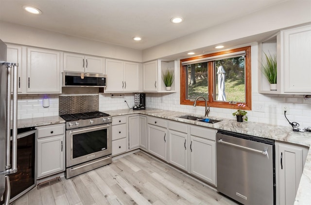 kitchen featuring white cabinetry, sink, light hardwood / wood-style floors, and appliances with stainless steel finishes