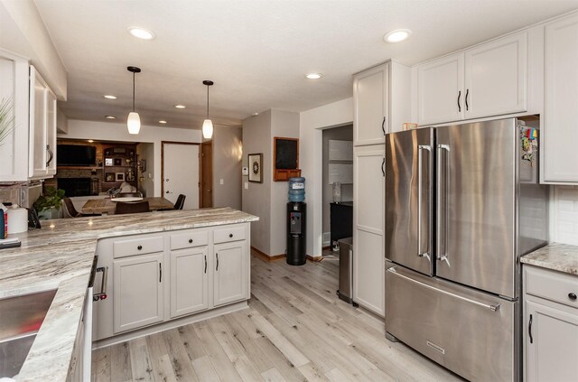 kitchen with white cabinetry, hanging light fixtures, light stone counters, and high quality fridge