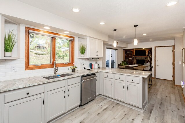 kitchen with pendant lighting, white cabinetry, stainless steel dishwasher, kitchen peninsula, and light stone countertops