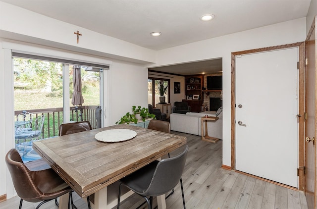 dining room featuring light hardwood / wood-style flooring and a brick fireplace