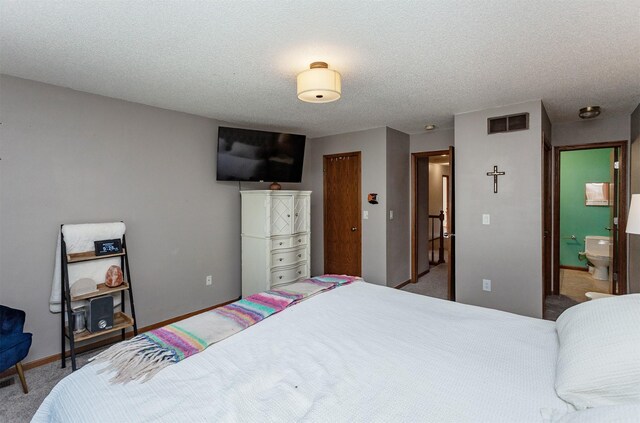 carpeted bedroom with connected bathroom and a textured ceiling