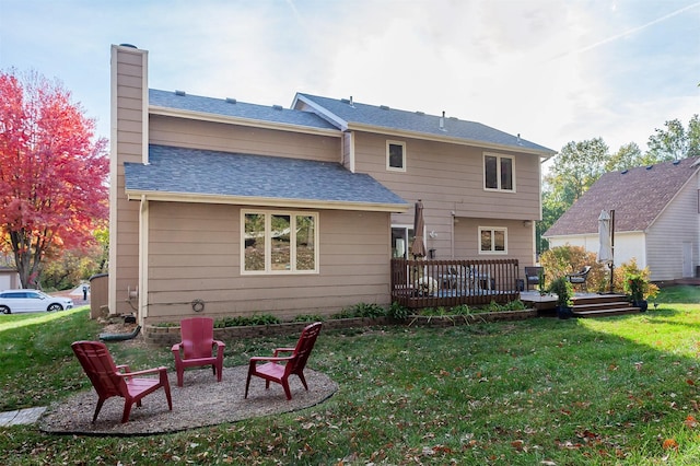 back of house with a fire pit, a deck, and a lawn