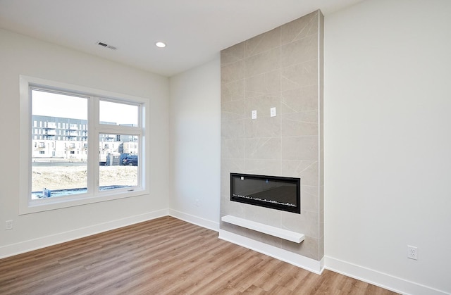 unfurnished living room featuring a tile fireplace and hardwood / wood-style flooring