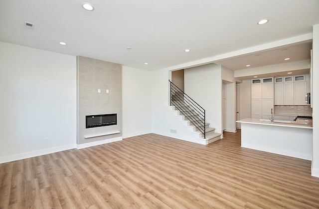 unfurnished living room featuring light hardwood / wood-style floors and a tiled fireplace