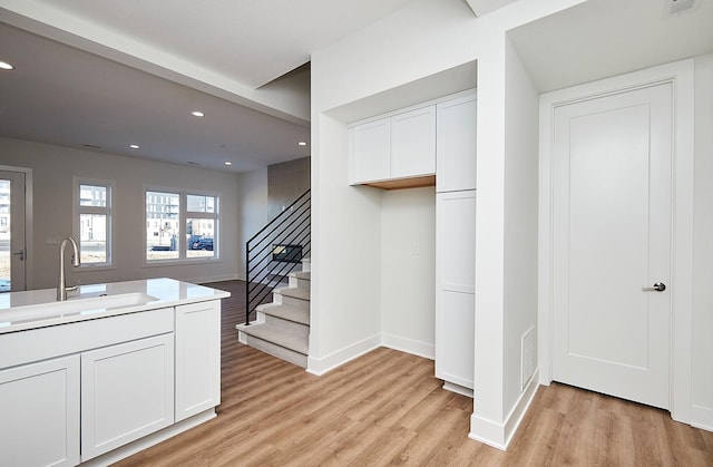 kitchen with white cabinetry, sink, and light hardwood / wood-style flooring