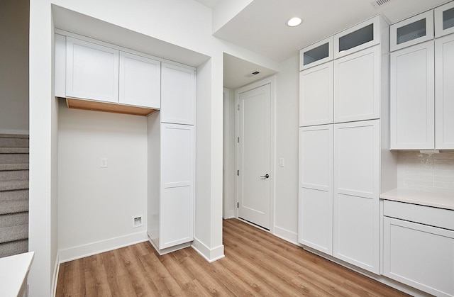 kitchen featuring white cabinets, decorative backsplash, and light hardwood / wood-style floors