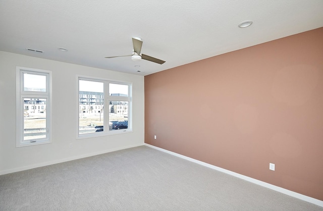 spare room featuring ceiling fan, light colored carpet, and a textured ceiling