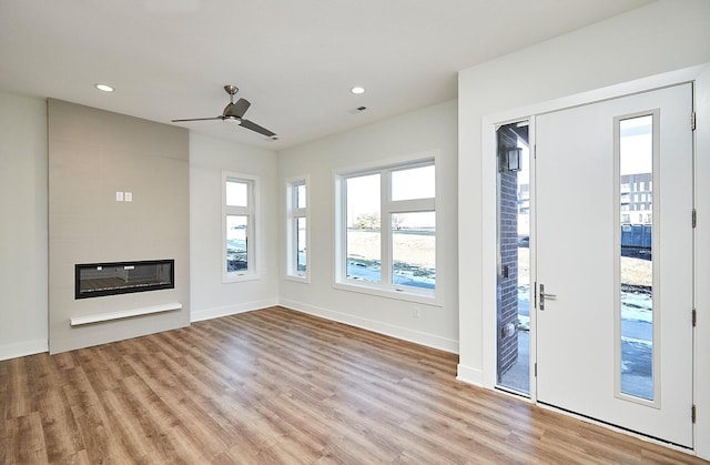 unfurnished living room featuring ceiling fan, light hardwood / wood-style floors, and a fireplace