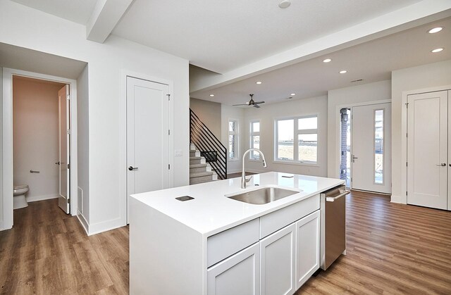 kitchen featuring sink, stainless steel dishwasher, an island with sink, white cabinets, and light wood-type flooring