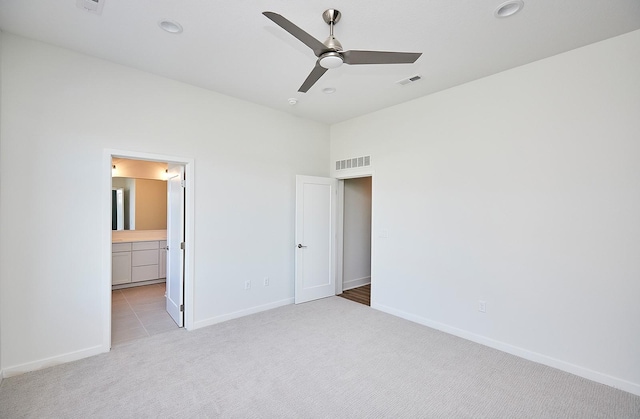 unfurnished bedroom featuring light carpet, ensuite bathroom, and ceiling fan