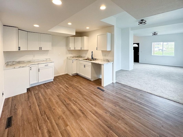 kitchen featuring white cabinetry, sink, light stone counters, and light hardwood / wood-style flooring