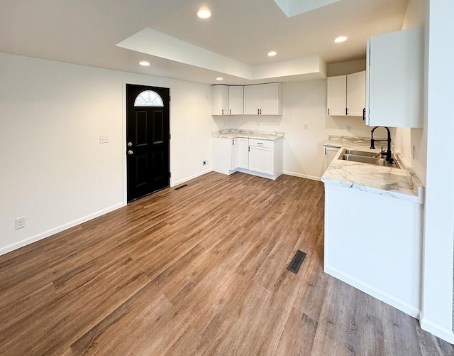 kitchen with sink, white cabinets, and light hardwood / wood-style flooring