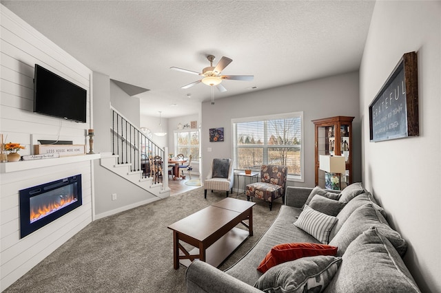 carpeted living room featuring ceiling fan with notable chandelier and a textured ceiling