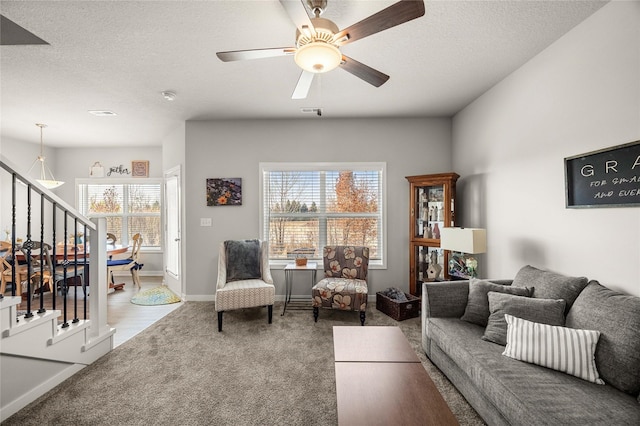 living room with ceiling fan, carpet floors, and a textured ceiling