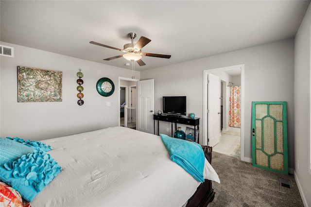 carpeted bedroom with ensuite bathroom and ceiling fan