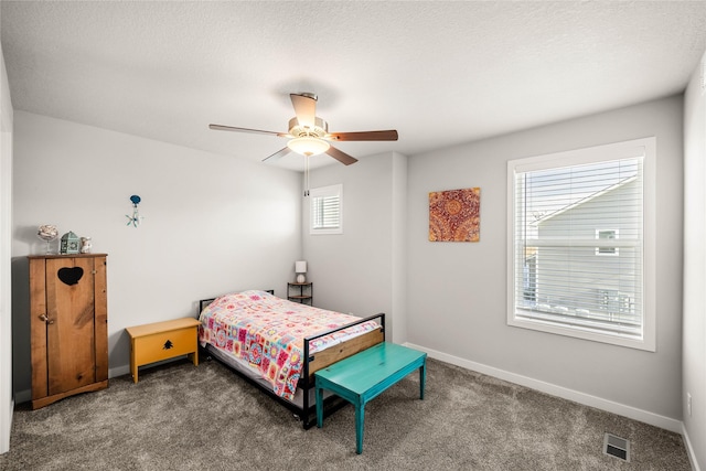 bedroom featuring multiple windows, ceiling fan, dark carpet, and a textured ceiling