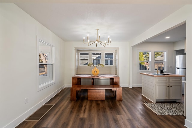 dining area with dark hardwood / wood-style flooring and an inviting chandelier