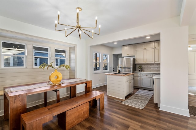 kitchen featuring sink, dark wood-type flooring, decorative backsplash, stainless steel fridge, and a kitchen island with sink