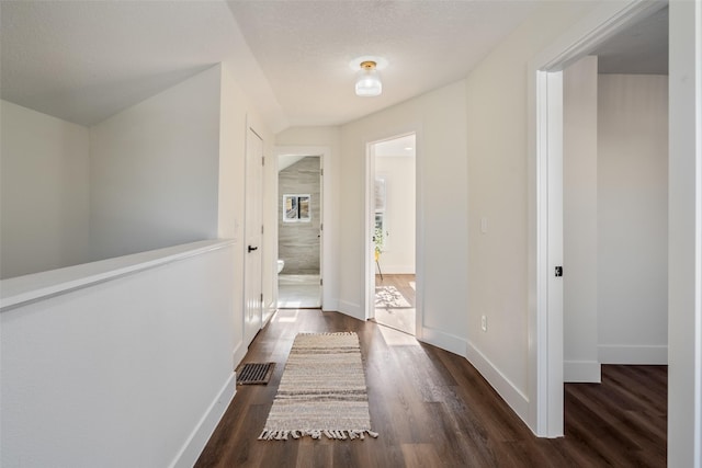 hallway featuring dark hardwood / wood-style flooring and a textured ceiling