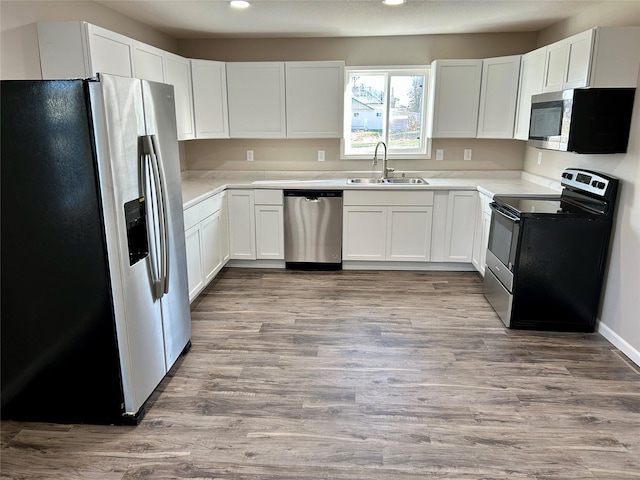 kitchen with stainless steel appliances, white cabinetry, light hardwood / wood-style floors, and sink