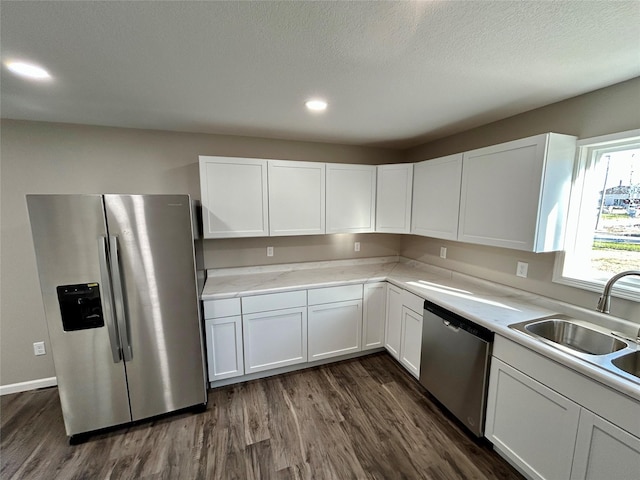 kitchen with dark hardwood / wood-style flooring, stainless steel appliances, white cabinetry, and sink