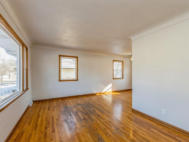 unfurnished room featuring hardwood / wood-style flooring, a textured ceiling, ceiling fan, and a wealth of natural light