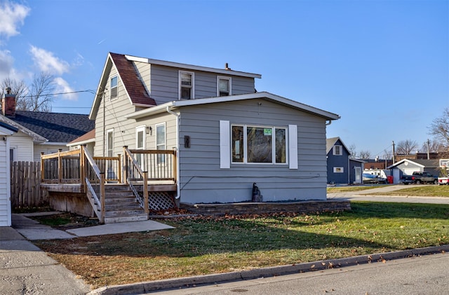 bungalow with a wooden deck and a front lawn