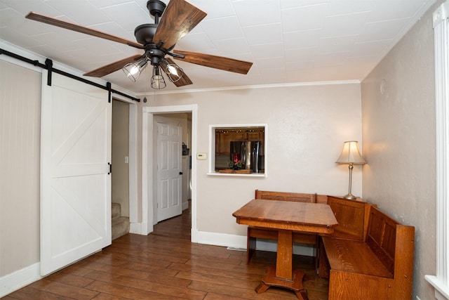 interior space with ornamental molding, a barn door, ceiling fan, and dark wood-type flooring