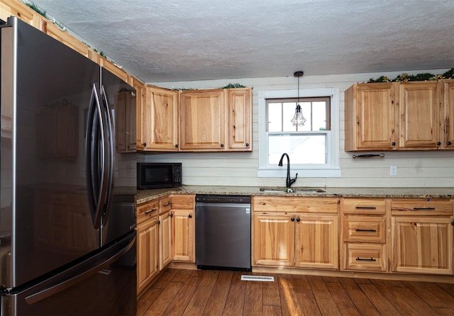 kitchen with sink, hanging light fixtures, dark hardwood / wood-style floors, light stone counters, and stainless steel appliances