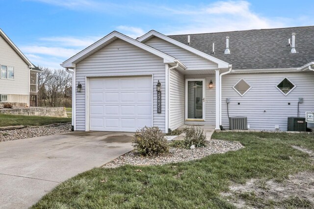 ranch-style house featuring cooling unit, a garage, and a front lawn