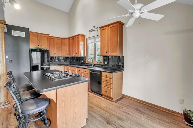 kitchen featuring black appliances, sink, ceiling fan, light wood-type flooring, and tasteful backsplash