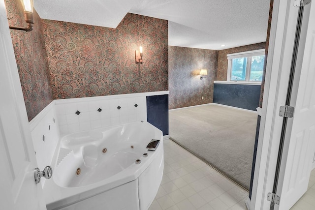 bathroom with tile patterned flooring, a tub to relax in, and a textured ceiling