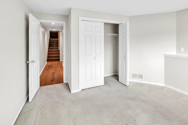 unfurnished bedroom featuring a closet and light colored carpet