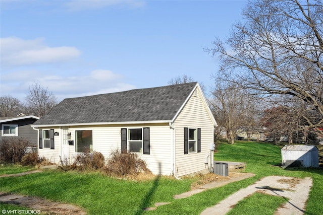 view of front of home featuring central AC, a shed, and a front yard