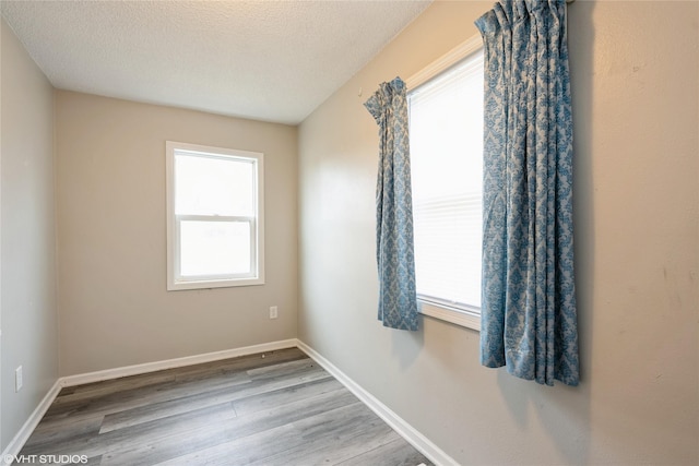 unfurnished room featuring light hardwood / wood-style flooring and a textured ceiling