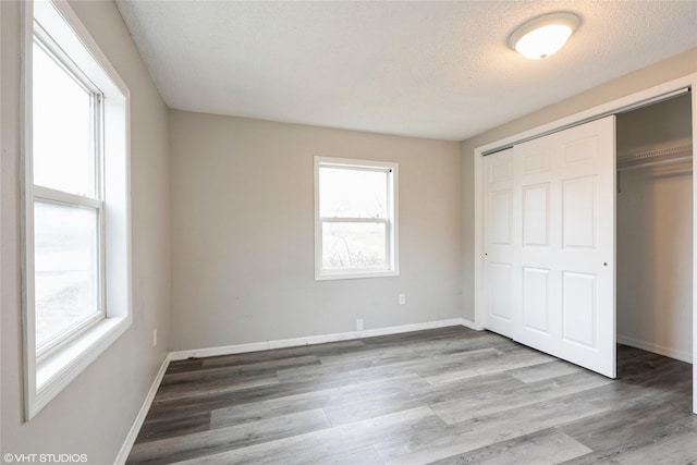 unfurnished bedroom featuring light wood-type flooring, a textured ceiling, and a closet