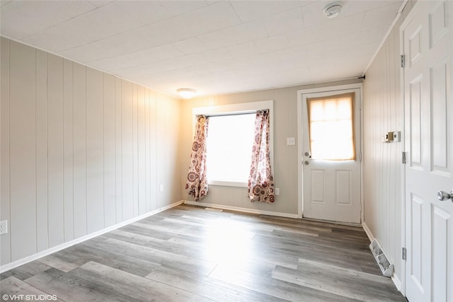 empty room featuring light wood-type flooring and wooden walls